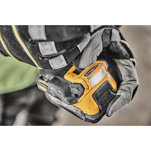 Gloved hand holding a DEWALT cordless drill with light illuminated, close-up view of tool.