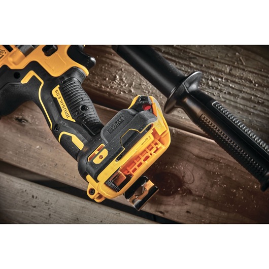 Close-up of a DEWALT cordless drill handle with battery, resting on wooden planks.