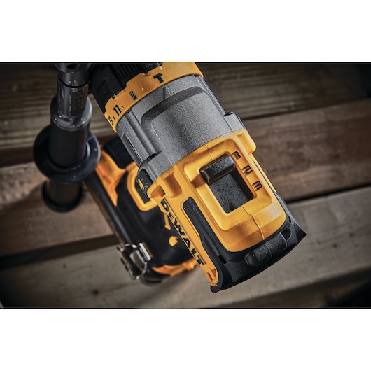 Close-up of a DEWALT cordless drill with handle and speed settings on a wooden surface.