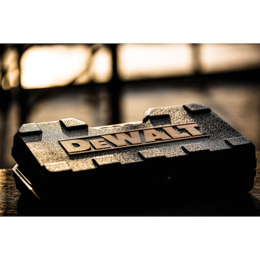 A close-up of a textured DEWALT hard plastic tool case with the DEWALT logo prominently displayed on top, set against a blurred background.