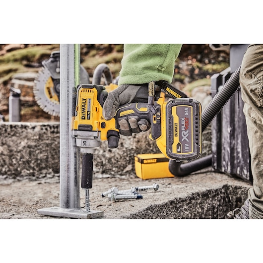 Close-up of DEWALT DCF894P2 impact wrench being used on a metal structure outdoors.