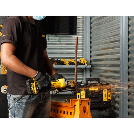 Worker using power tool on a construction site overlooking a city skyline by the water.