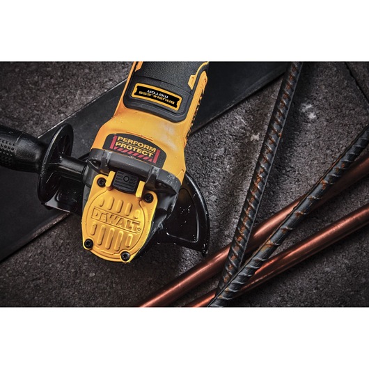DEWALT cordless angle grinder shown near metal rods on a concrete surface.
