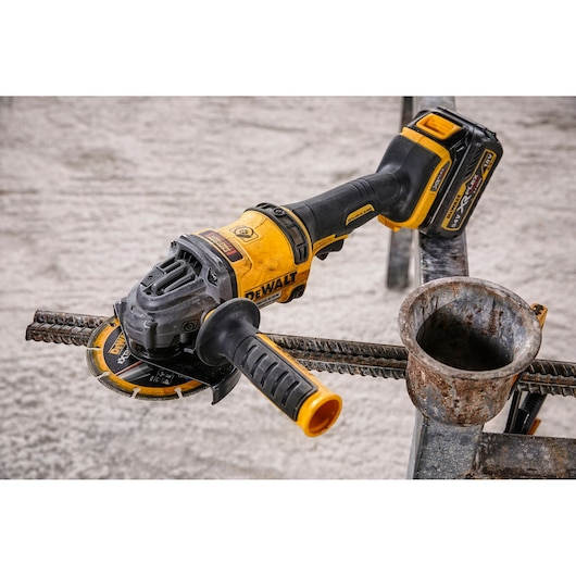 DEWALT cordless angle grinder cutting metal rebar at a construction site.