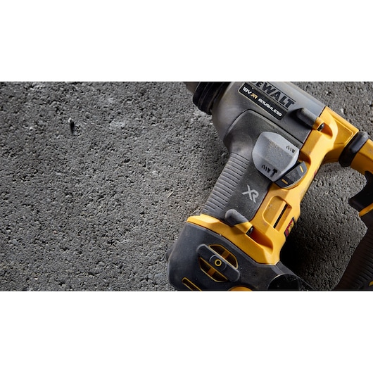Close-up of a DEWALT 18V XR brushless tool on rough concrete surface.