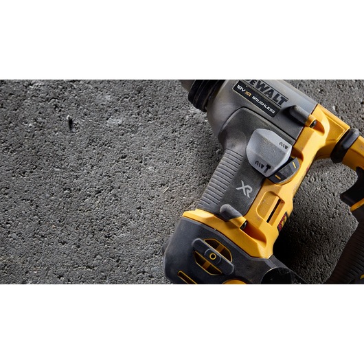 Close-up of a DEWALT 18V XR brushless cordless drill on rough concrete surface.