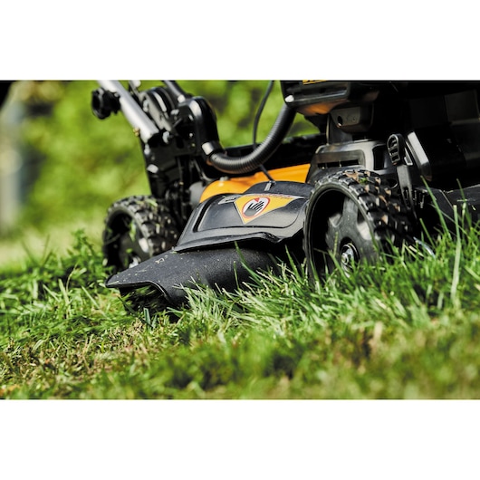 Close-up of a DEWALT lawn mower cutting grass outdoors.