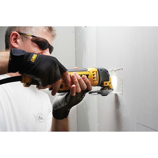 Person cuts drywall with yellow DEWALT DCS355D2 oscillating tool.
