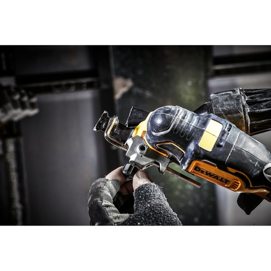 A DEWALT cordless oscillating multi-tool being used by a gloved hand in a workshop setting.