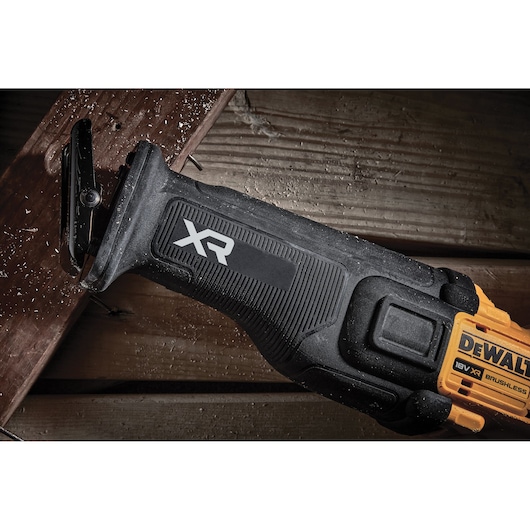 DEWALT XR 18V brushless reciprocating saw cutting wood, close-up of tool handle and blade.