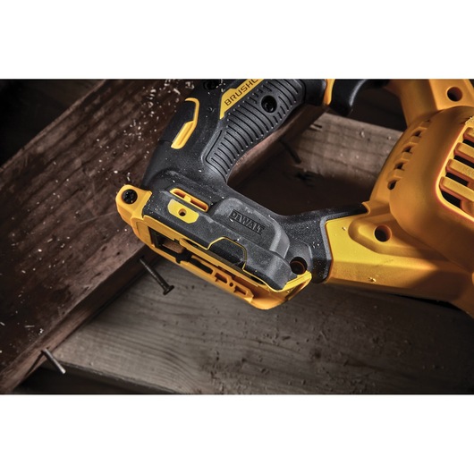 Close-up of a DEWALT cordless saw handle resting on wood, showing grip texture and brand logo.