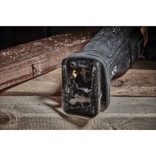 Close-up of a DEWALT reciprocating saw resting on wood, showing the blade slot and tool surface with sawdust.