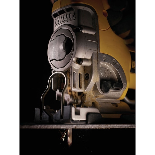 Close-up of a DEWALT jigsaw in use, cutting material. Tool details and blade are visible.