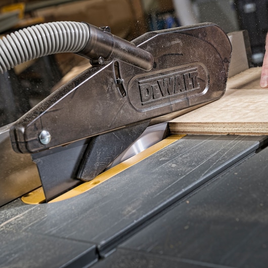 DEWALT saw blade cutting wood with dust extraction guard in workshop.