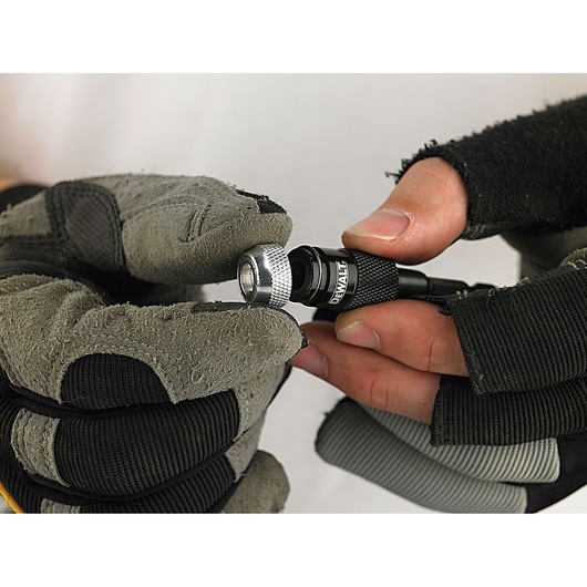 Gloved hands holding and adjusting a DEWALT drill bit holder.