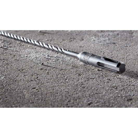 A close-up of a DEWALT DT8911 metal drill bit lying on a rough concrete surface.