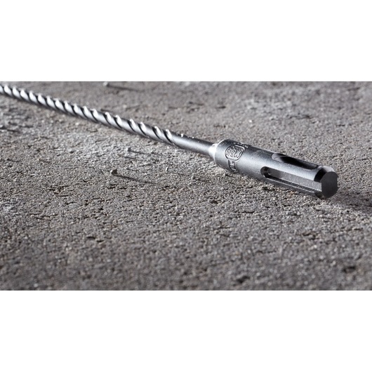 Close-up of a DEWALT DT8918 SDS drill bit placed on a rough concrete surface.