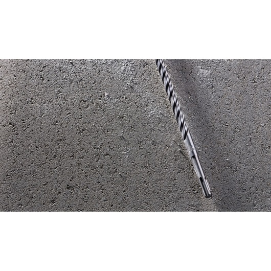 A DEWALT DT8930 masonry drill bit inserted into a concrete surface, showing its spiral design and robust construction.