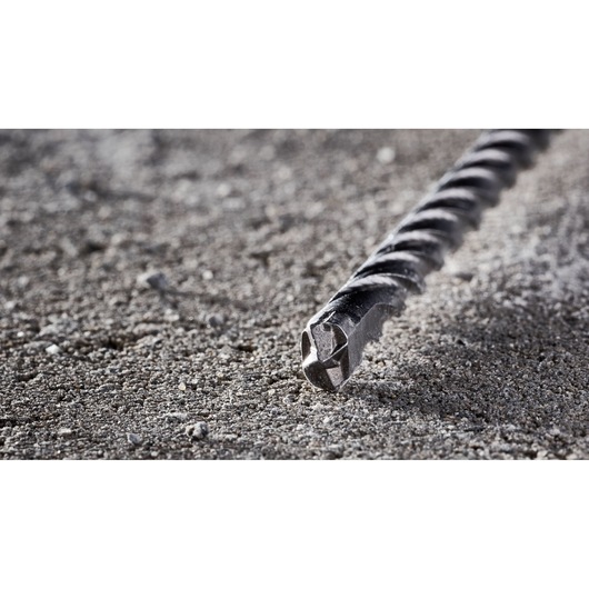 Close-up of a DEWALT DT8935 rotary hammer drill bit lying on a rough concrete surface.