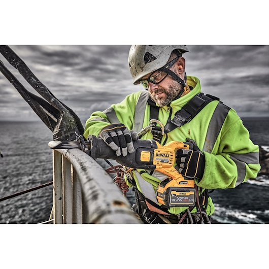 Worker uses DEWALT tool, SKUs DT99553, DT99553-QZ, in outdoor industrial setting near water.