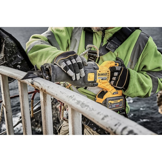 DEWALT DT99553, DT99553-QZ saw in use outdoors. Worker cuts metal railing with power tool.