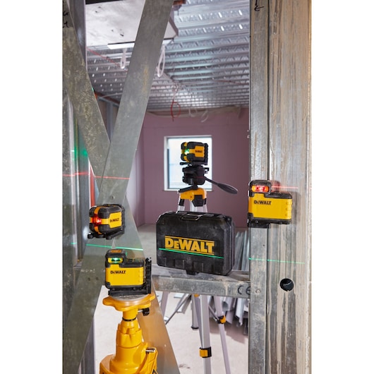 DEWALT laser levels and case setup on a construction site with metal framing and tripods.