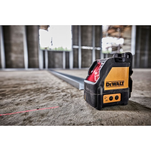 DEWALT laser level emits a red line on a construction site floor for accurate measurements.