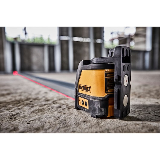 DEWALT DW088K laser level projects a red line across a construction floor for precise alignment.