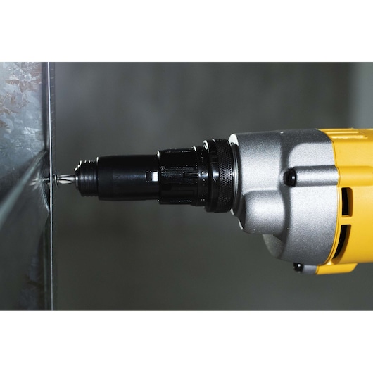 Close-up view of a DEWALT DW268 power screwdriver being used to drive a screw into a metal surface.