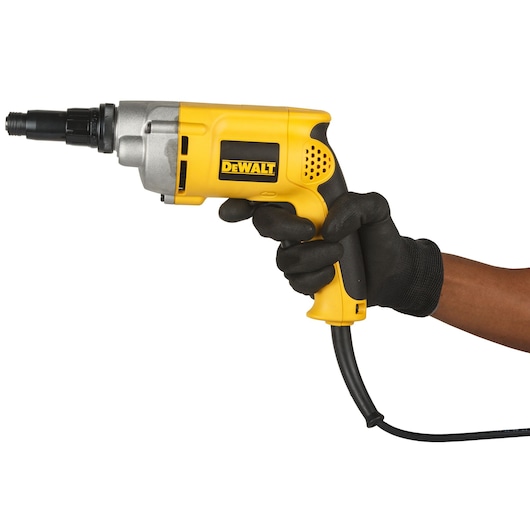 A person wearing black gloves is holding a yellow DEWALT electric screwdriver with a cord, model DW269, against a white background.