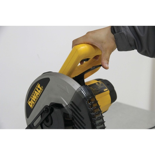 Hand holds the handle of a DEWALT circular saw, focusing on the yellow and black tool's grip area.