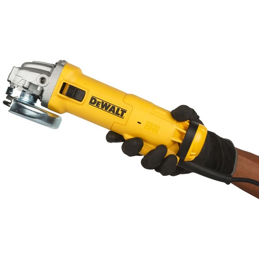 A person wearing black gloves is holding a yellow DEWALT angle grinder model DWE4215. The tool has a metal grinding disc and visible branding on the side.