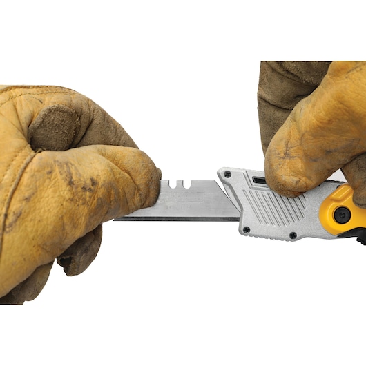 Gloved hands change a blade on a DEWALT utility knife model DWHT10429-0 against a white background.