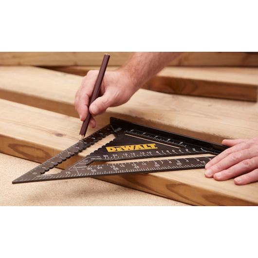 Person marking wood with a pencil using a DEWALT triangular square tool for precise measurements.