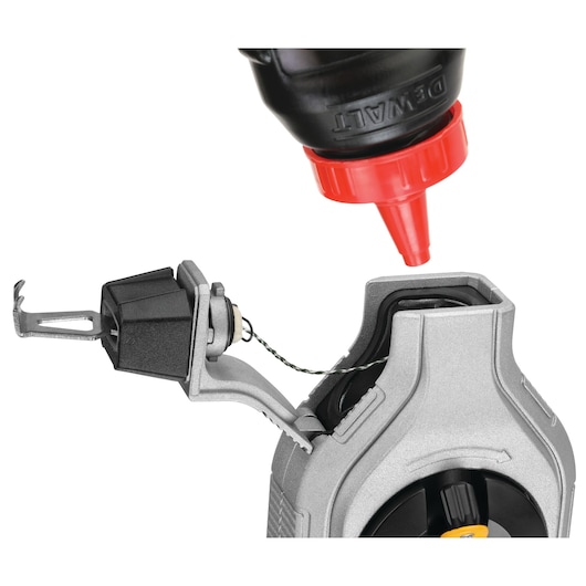 Close-up of a DEWALT chalk line reel being refilled with chalk powder from a bottle with a red nozzle.