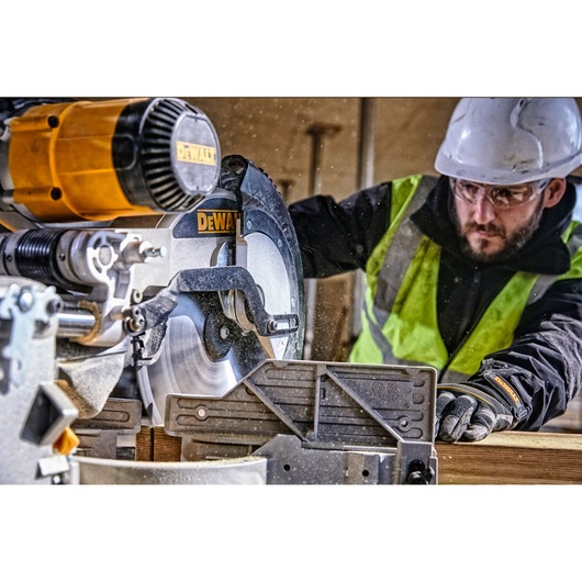 DEWALT DWS780, DWS780KIT saw in use at construction site. Worker in safety gear. Photography product category.