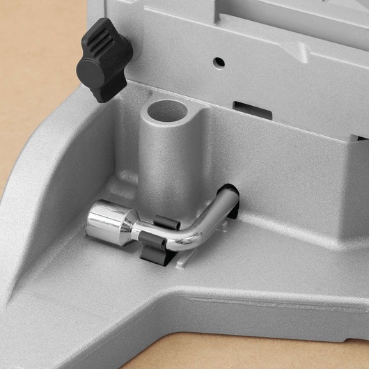 Close-up of a metallic component of a DEWALT machine, showing a silver L-shaped metal rod attached to a gray base, with a black knob above.