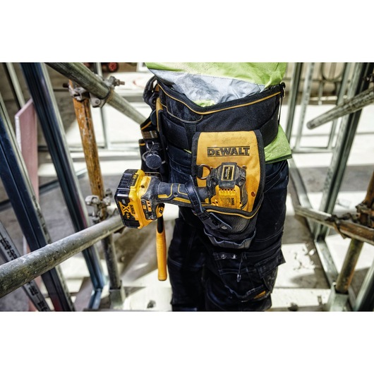 DEWALT tool holster with drill attached to a worker's belt on a construction site.