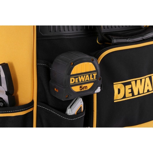 DEWALT 5m tape measure in a black and yellow tool bag pocket, with pliers and a utility knife visible.