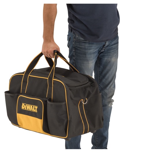 Person holding a black and yellow DEWALT tool bag with multiple pockets and carrying handles.